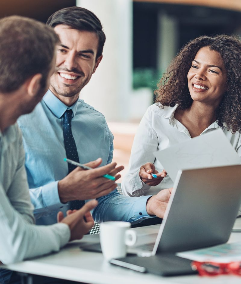 Three colleagues smiling during meeting with laptop