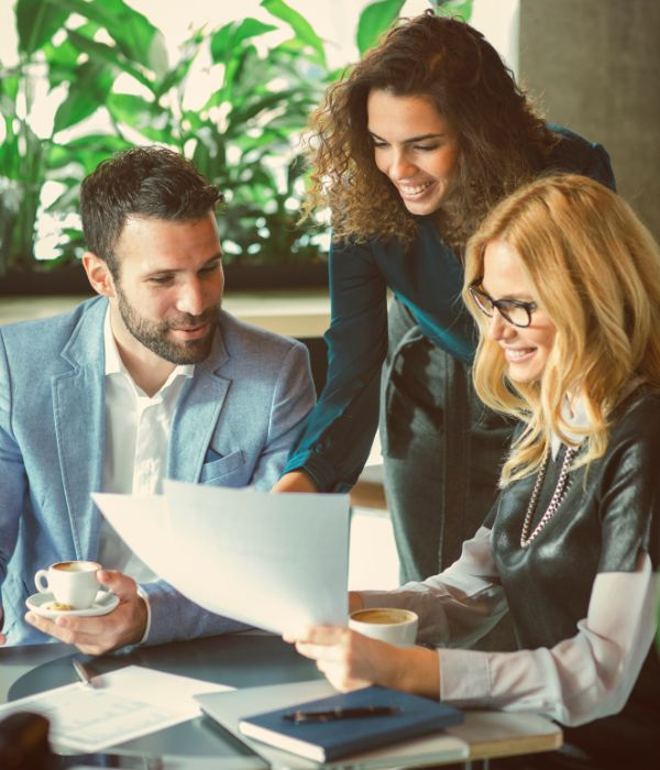 Three colleagues reviewing documents over coffee