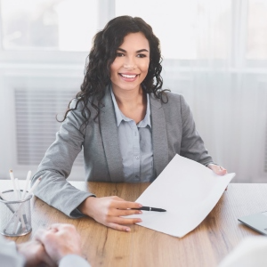 Smiling businesswoman at desk holding document